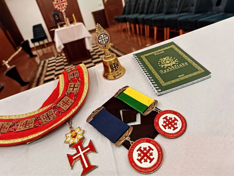 Insígnias do Apostolado dispostas sobre o altar: colar, comendas, sineta ritual e o Ritual 2022.